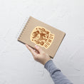 Load image into Gallery viewer, Hand holding a brown notebook with 'Howdy' design on a light gray background